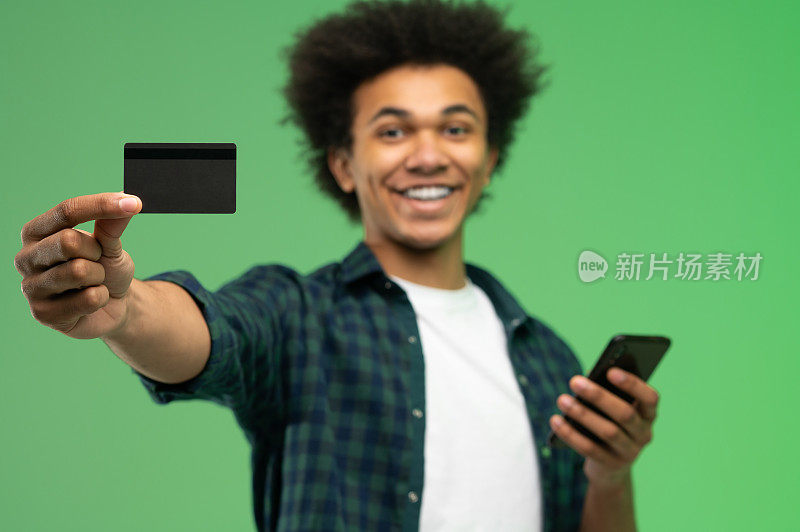 African american young guy with smartphone and credit card in hands
